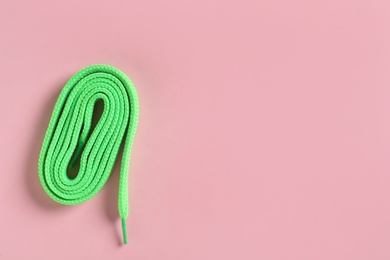 Photo of Green shoelace on pink background, top view. Space for text