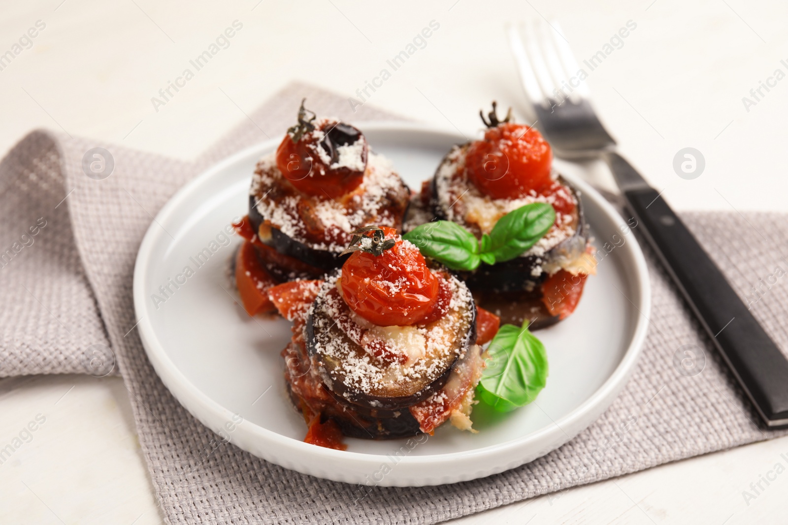 Photo of Baked eggplant with tomatoes, cheese and basil served on white wooden table