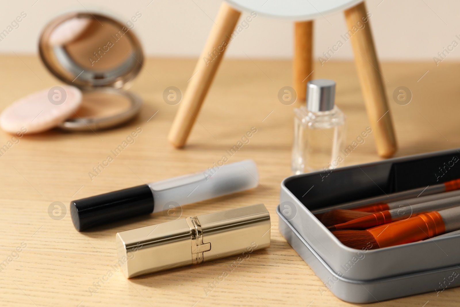 Photo of Makeup products and perfume on wooden dressing table, closeup