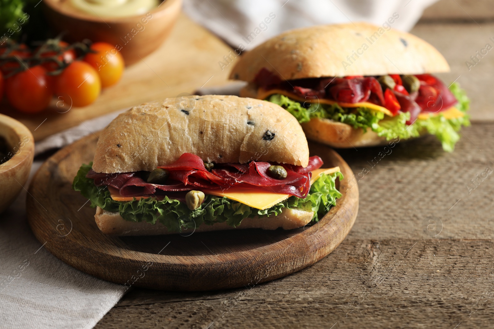 Photo of Delicious sandwiches with bresaola, lettuce and cheese on wooden table