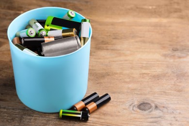 Used batteries and bucket on wooden table, space for text