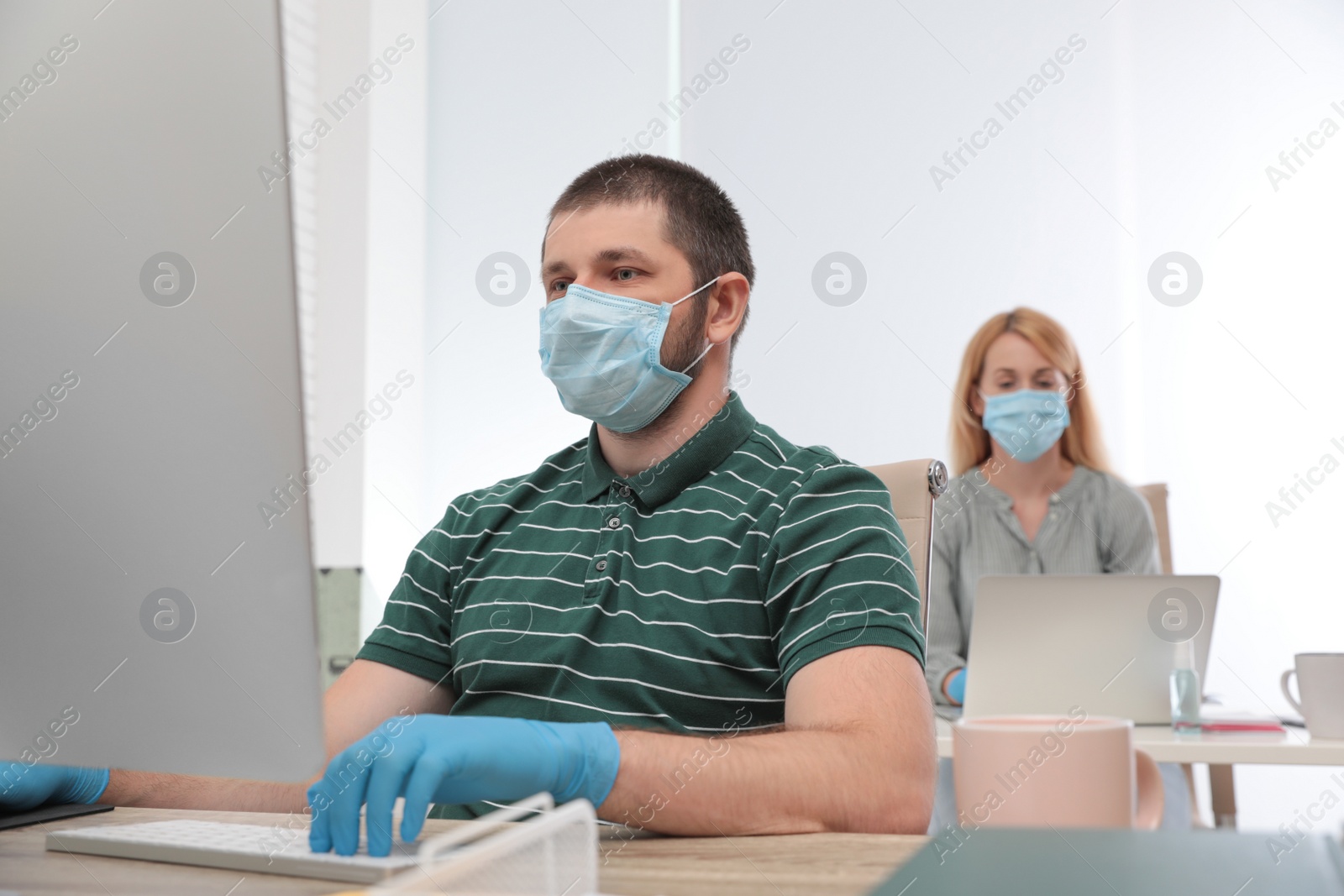 Photo of Office employees in respiratory masks at workplace