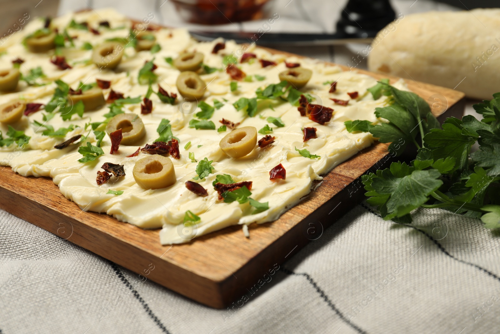 Photo of Fresh butter board with cut olives, sun-dried tomatoes and parsley on table, closeup