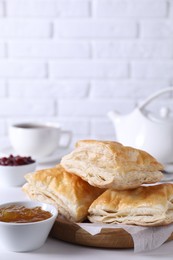 Delicious puff pastry served on white wooden table against brick wall, space for text