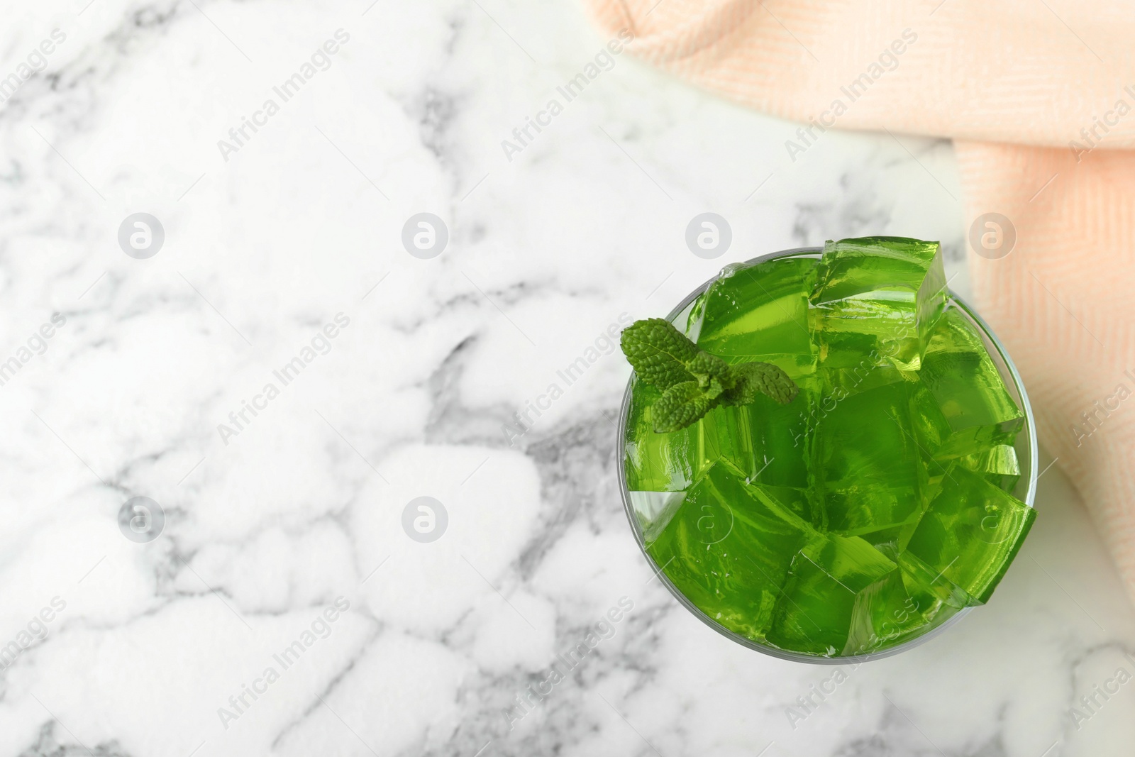 Photo of Kiwi jelly in bowl on marble table, top view. Space for text