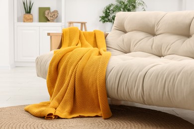 Comfortable sofa with orange blanket in living room