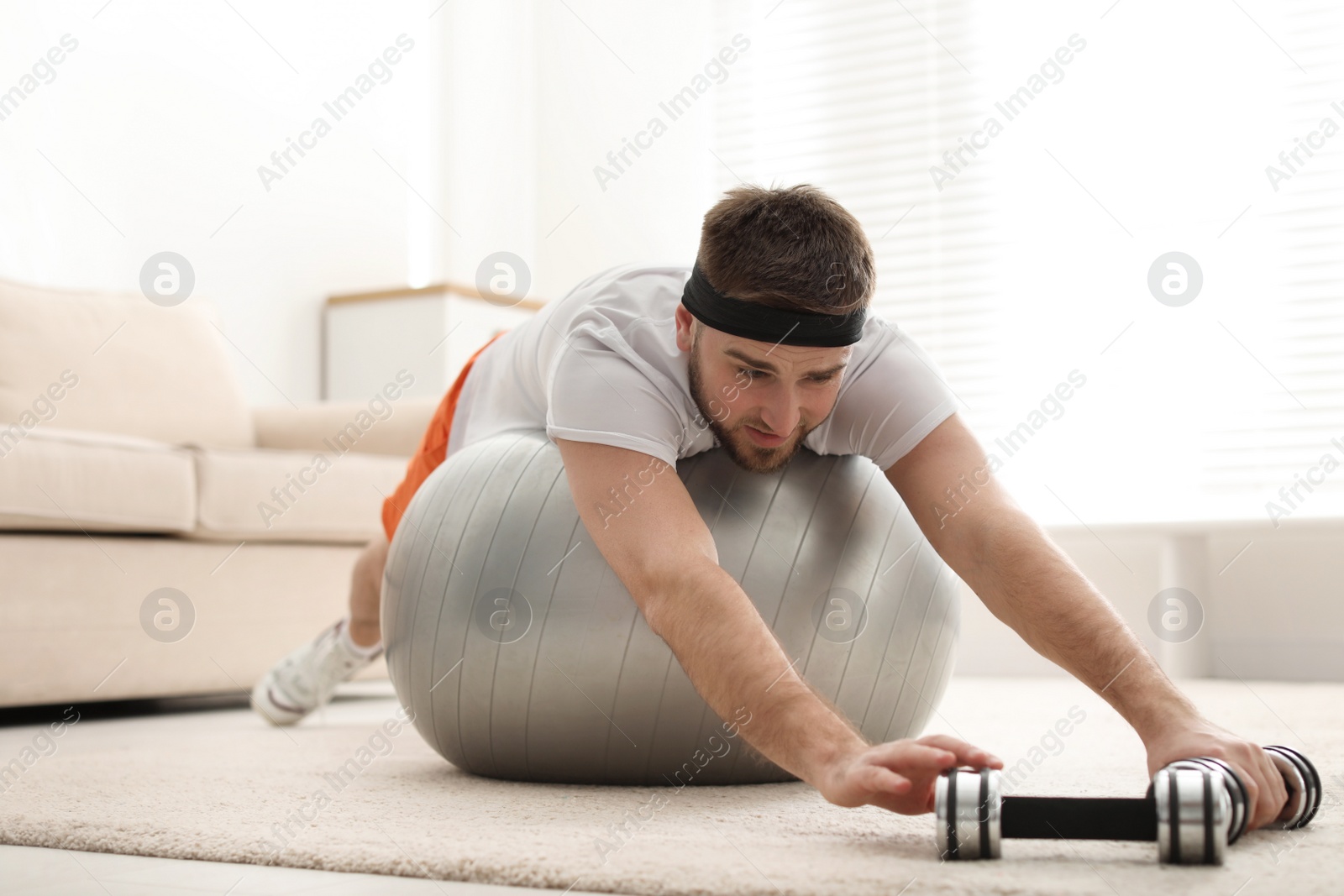 Photo of Lazy young man with sport equipment at home