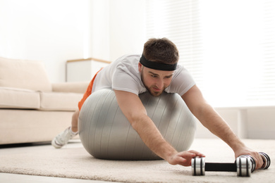 Lazy young man with sport equipment at home