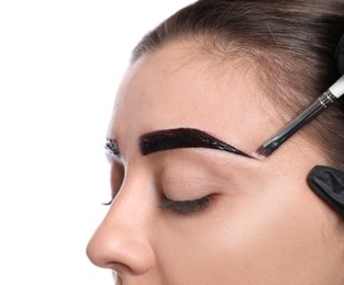 Photo of Beautician applying tint during eyebrows correction procedure on white background, closeup