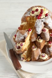 Delicious Pandoro Christmas tree cake with powdered sugar and berries on white wooden table, closeup