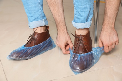 Photo of Man putting on blue shoe covers, closeup