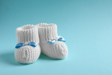 Photo of Handmade baby booties on color background. Space for text