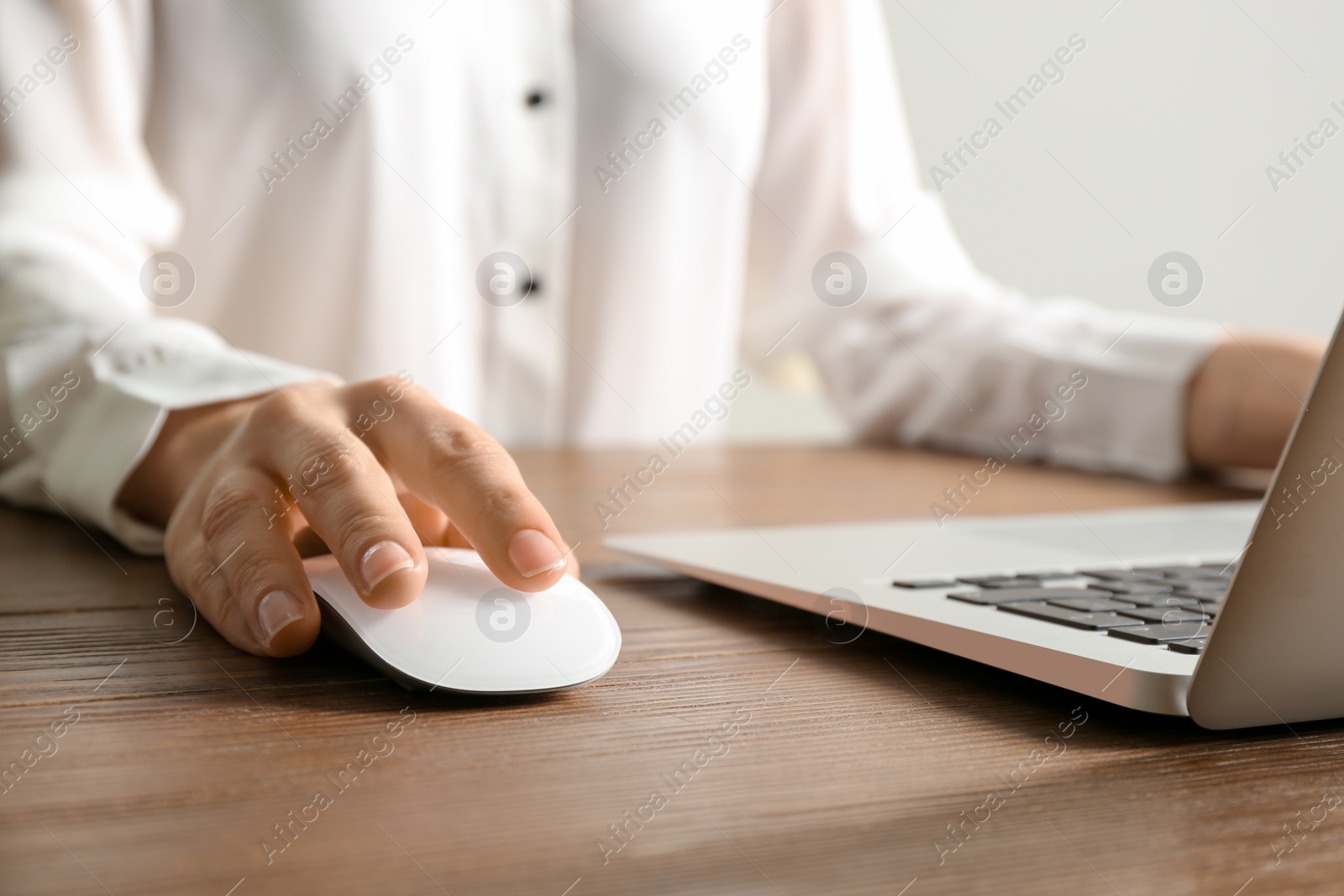 Photo of Woman using computer mouse with laptop at table, closeup