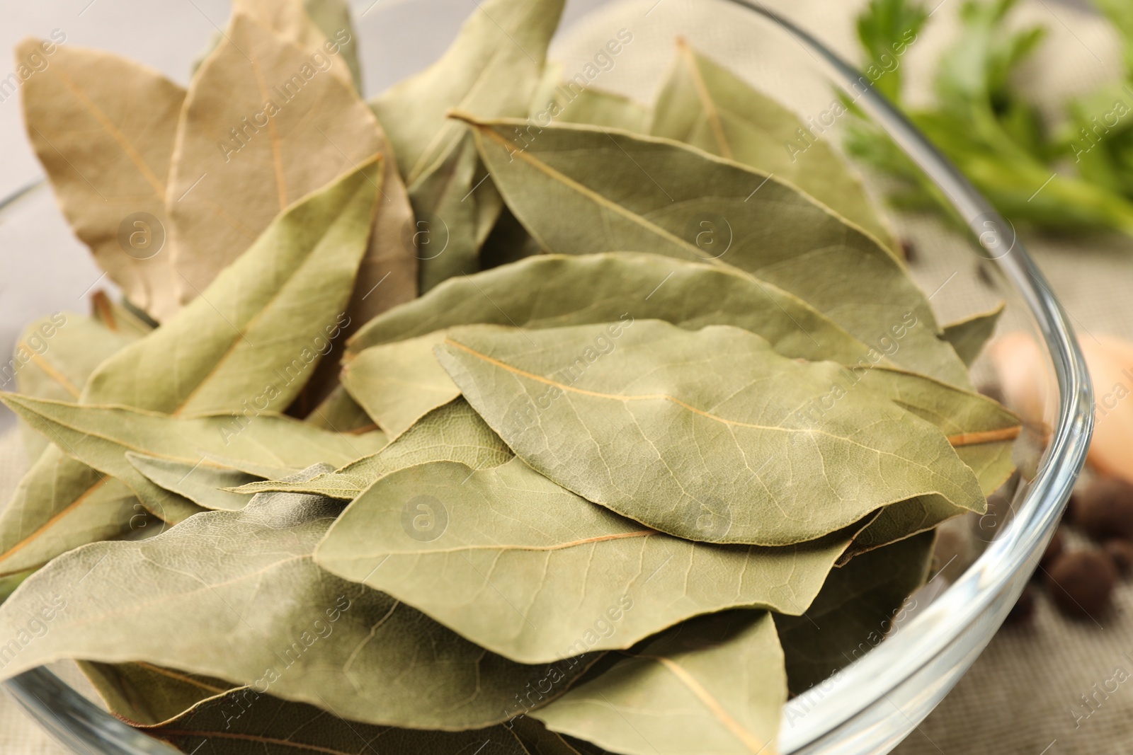 Photo of Aromatic bay leaves in glass bowl, closeup