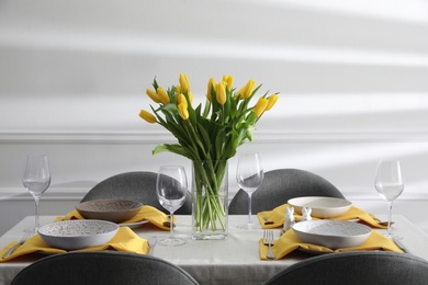 Beautiful Easter table setting with yellow tulips indoors