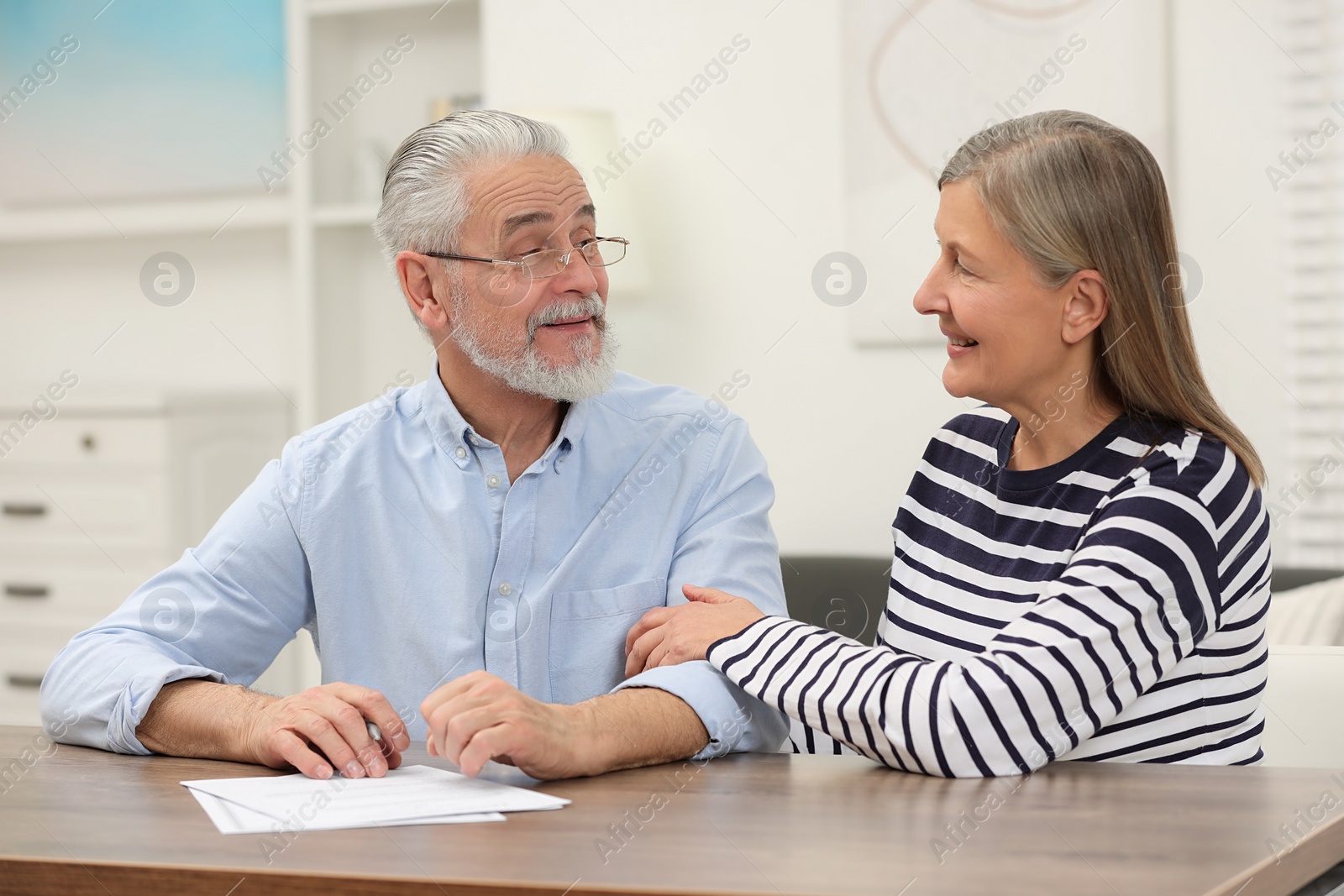 Photo of Happy senior couple signing Last Will and Testament indoors