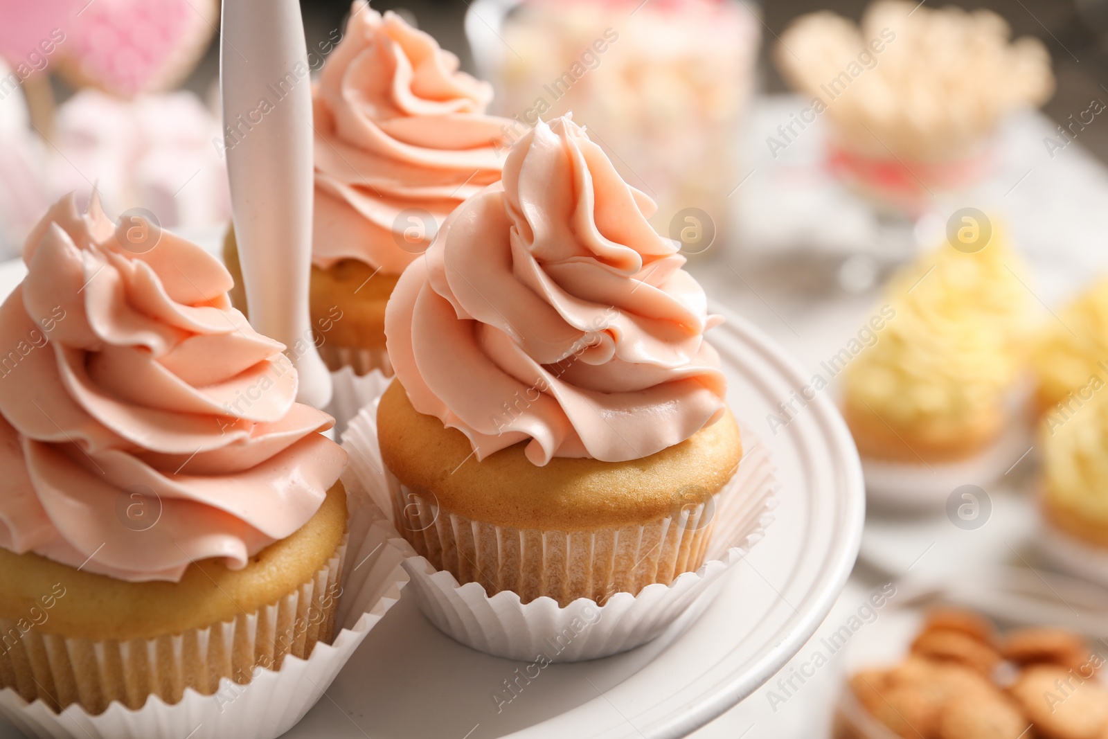 Photo of Stand with tasty cupcakes on table, closeup. Candy bar