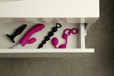 Vibrator, anal plug, balls and beads in drawer indoors, top view. Sex toys