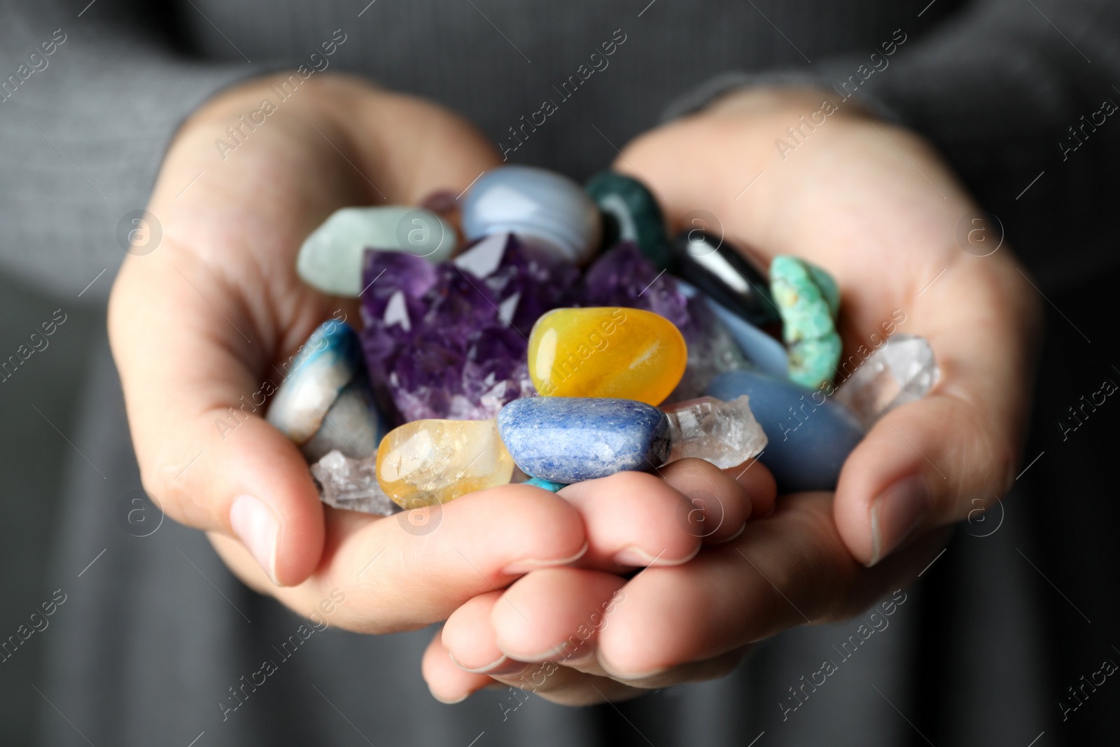 Photo of Woman holding pile of different gemstones, closeup