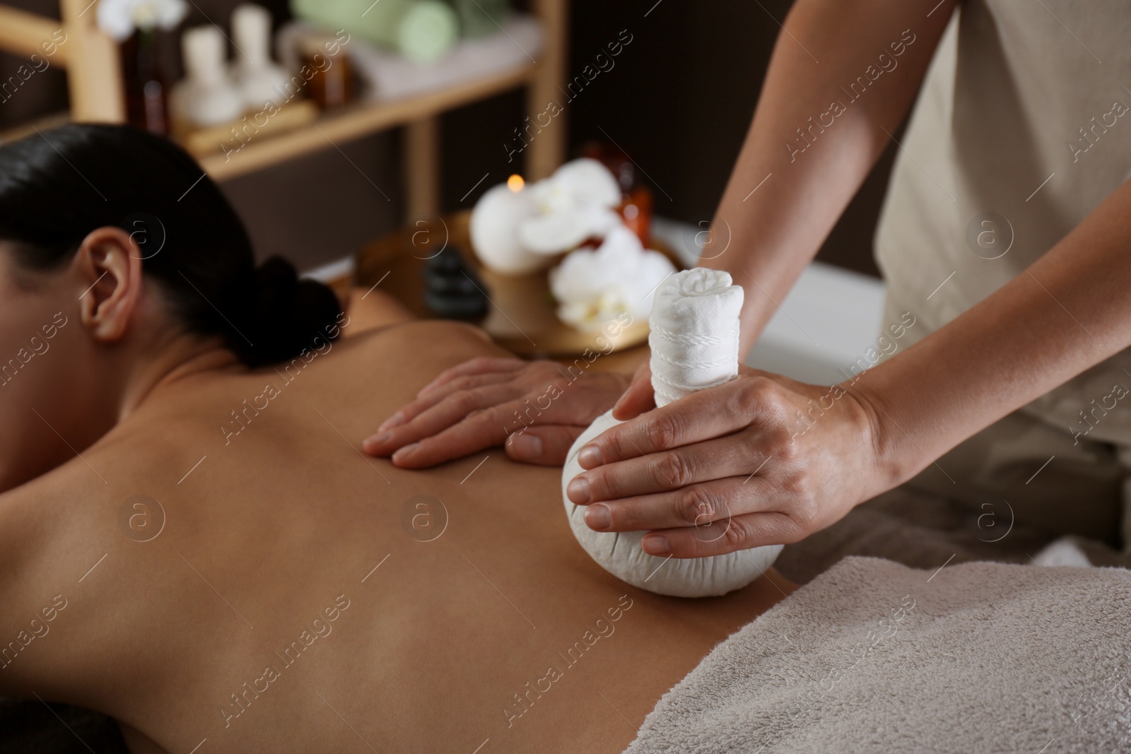 Photo of Young woman receiving herbal bag massage in spa salon, closeup