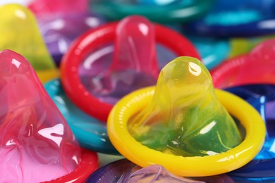 Colorful unpacked condoms as background, closeup view. Safe sex