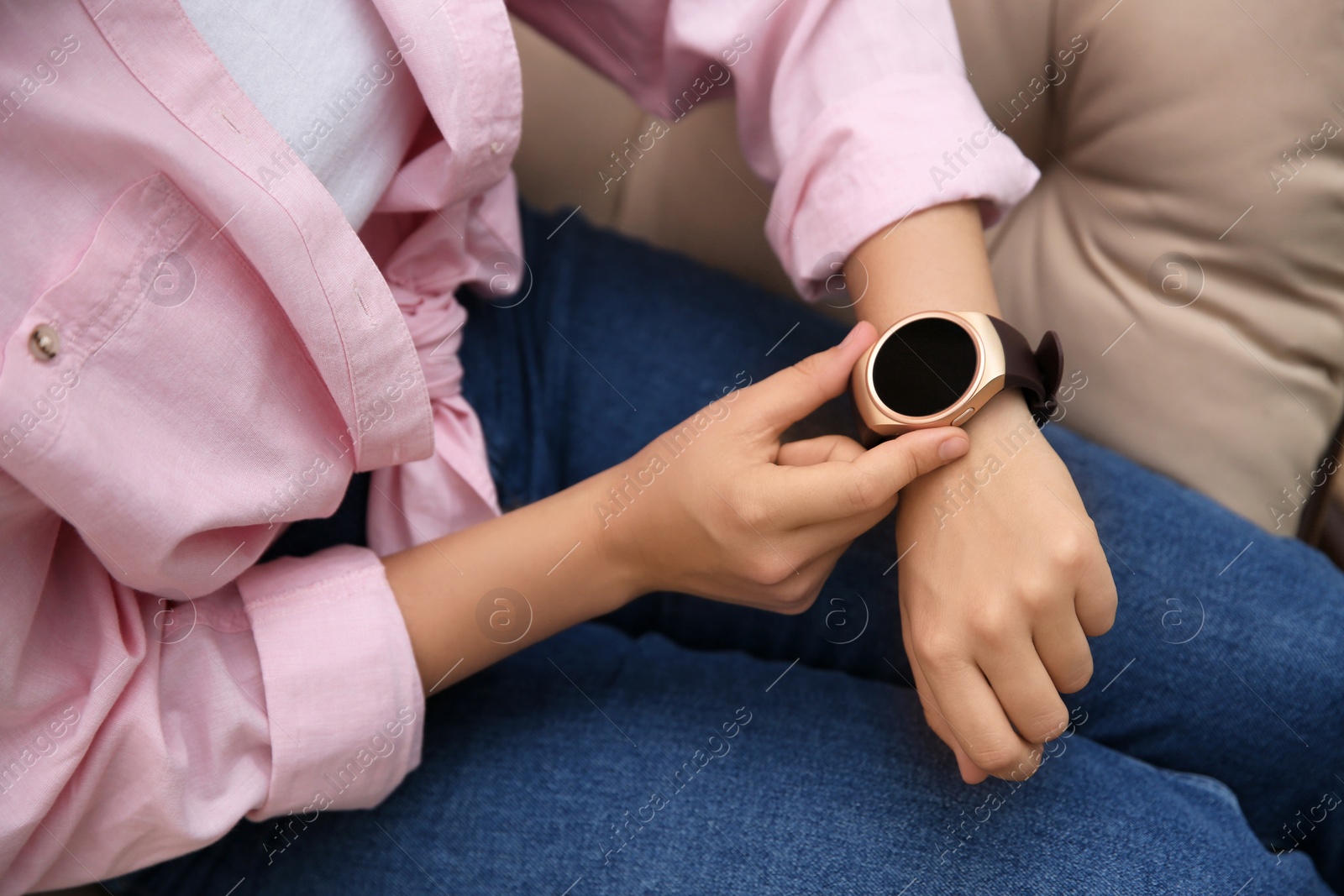 Photo of Woman using modern smartwatch in armchair, closeup