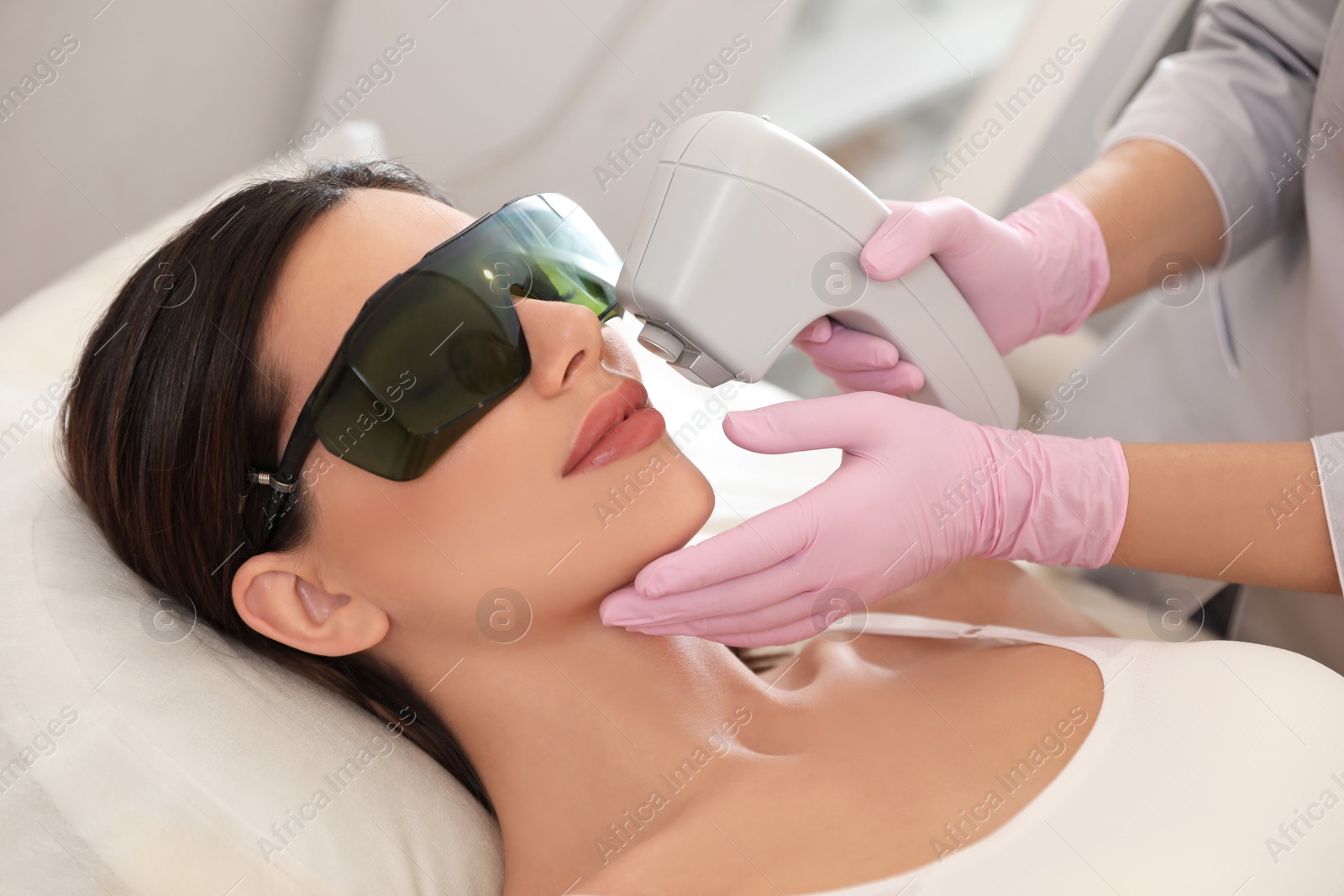 Photo of Young woman undergoing laser epilation procedure in beauty salon