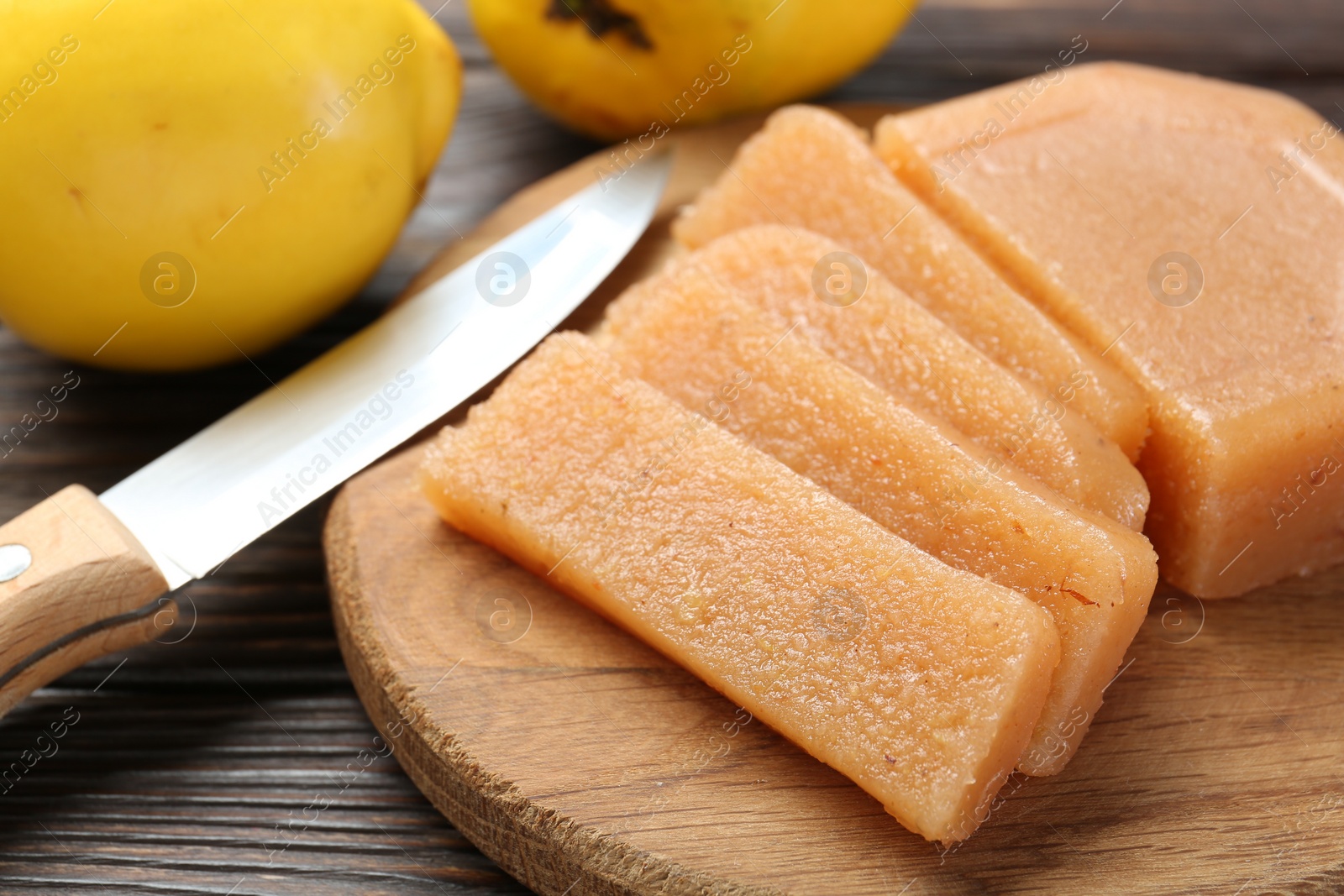 Photo of Tasty sweet quince paste, fresh fruits and knife on wooden table, closeup