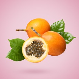 Image of Delicious ripe granadillas with green leaves falling on pink background