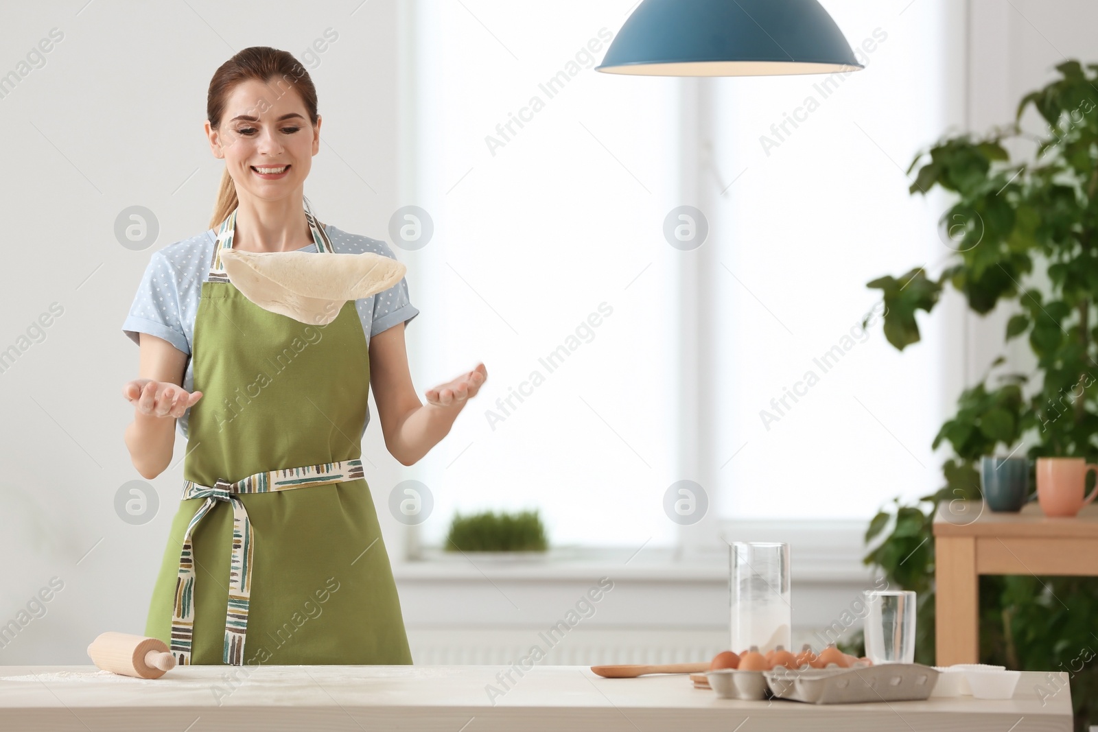 Photo of Young woman with raw dough in kitchen