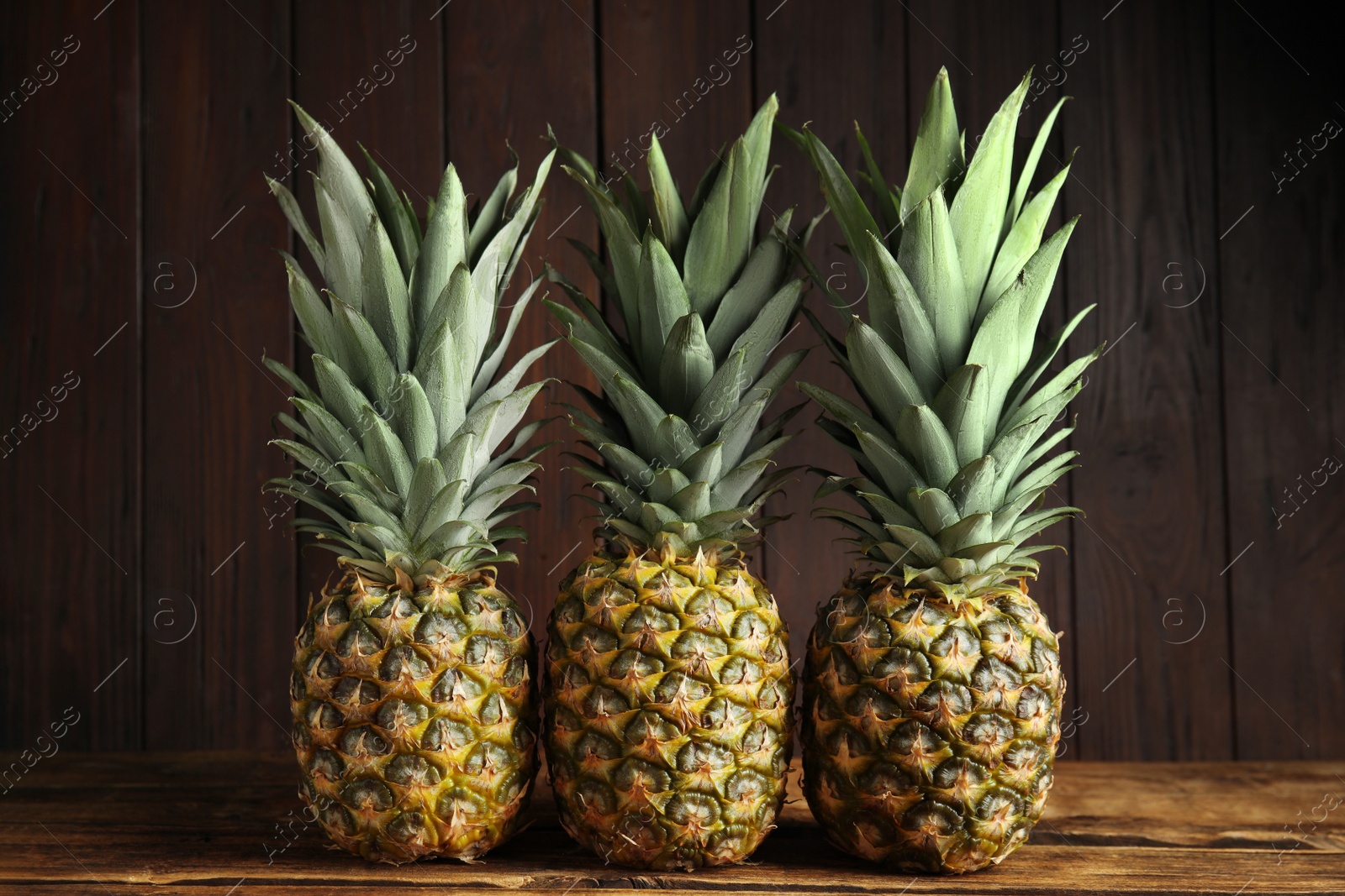 Photo of Fresh ripe juicy pineapples on wooden table