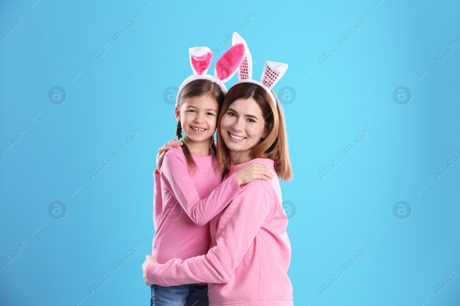 Photo of Happy woman and daughter with bunny ears on color background