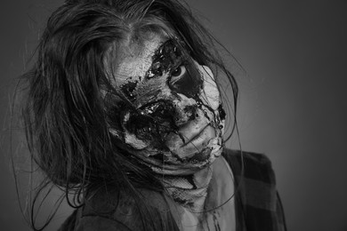 Photo of Scary zombie on dark background, black and white effect. Halloween monster