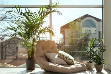 Photo of Cozy place with armchair pillow and potted plants at home