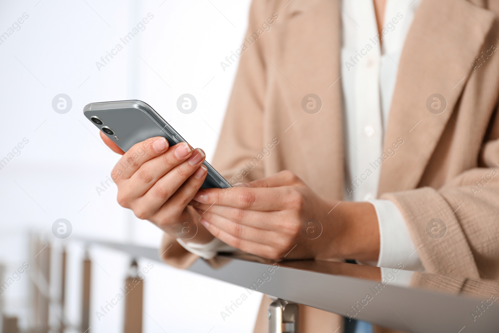 Photo of Young woman using modern smartphone indoors, closeup