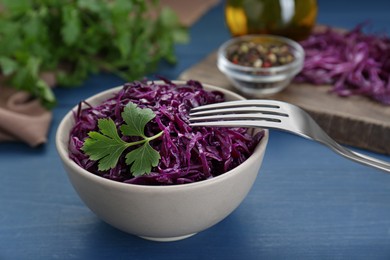 Photo of Tasty red cabbage sauerkraut with parsley on light blue wooden table