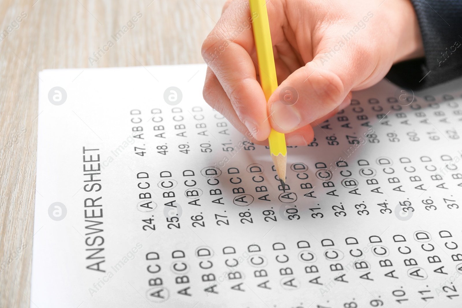 Photo of Student filling answer sheet at table, closeup