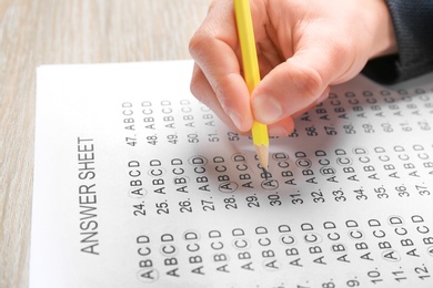 Photo of Student filling answer sheet at table, closeup