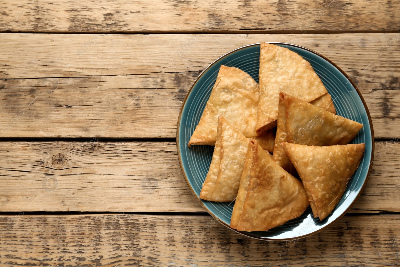 Photo of Fresh delicious crispy samosas on wooden table, top view. Space for text