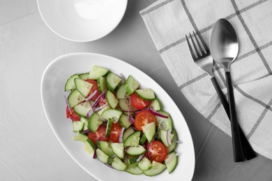 Plate of vegetarian salad with cucumber, tomato and onion served on table, flat lay