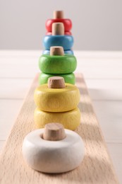 Photo of Motor skills development. Stacking and counting game pieces on white table, closeup