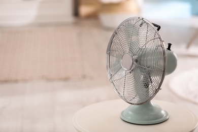 Photo of Modern electric fan on white table indoors. Space for text