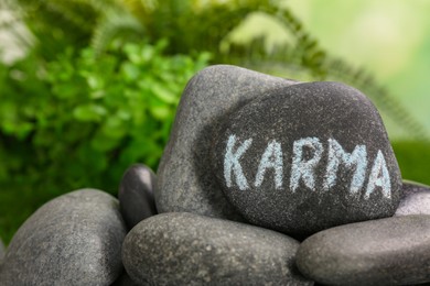 Stone with word Karma on blurred background, closeup. Space for text