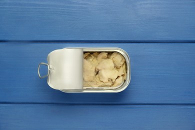 Open tin can of tasty cod liver on blue wooden table, top view