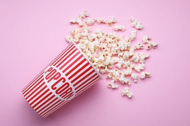 Photo of Bucket of tasty popcorn on pink background, flat lay