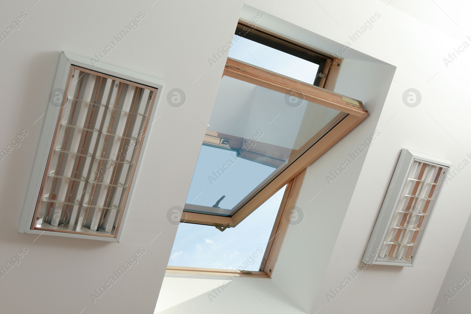 Photo of Open skylight roof window on slanted ceiling in attic room, bottom view