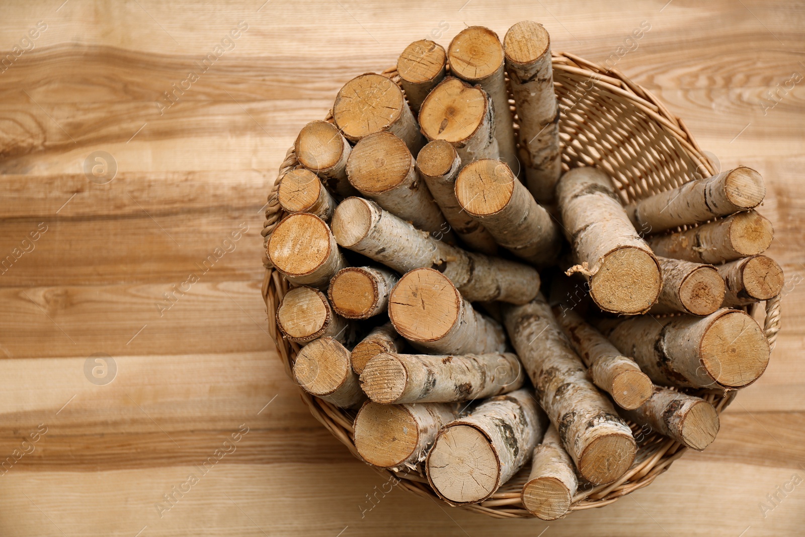 Photo of Wicker basket with firewood on floor indoors, top view