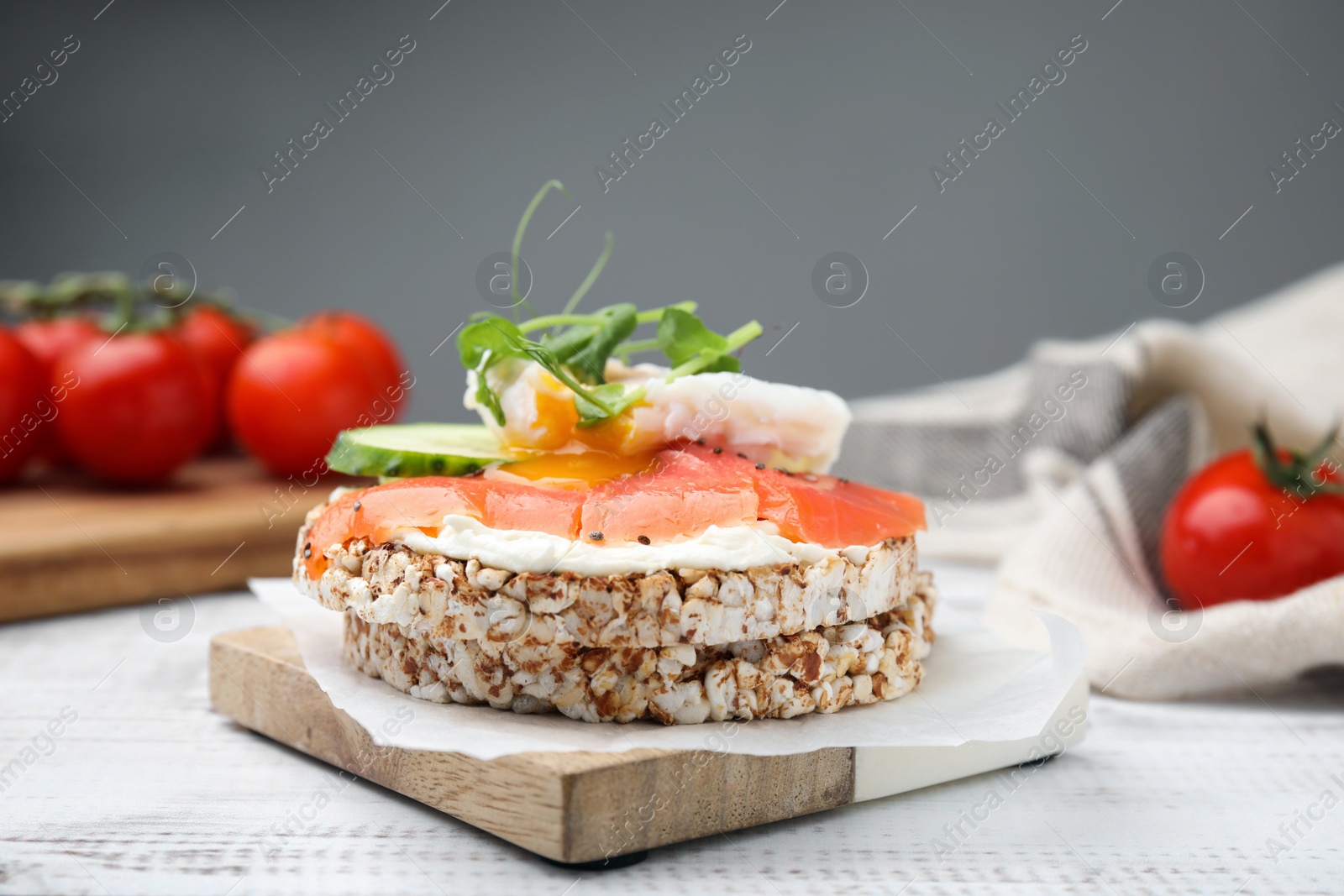 Photo of Crunchy buckwheat cakes with salmon, poached egg and cucumber slices on white wooden table