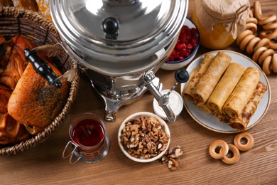 Photo of Traditional Russian samovar and treats on wooden table, top view