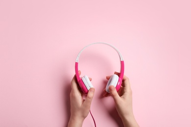 Woman holding stylish headphones on color background, closeup